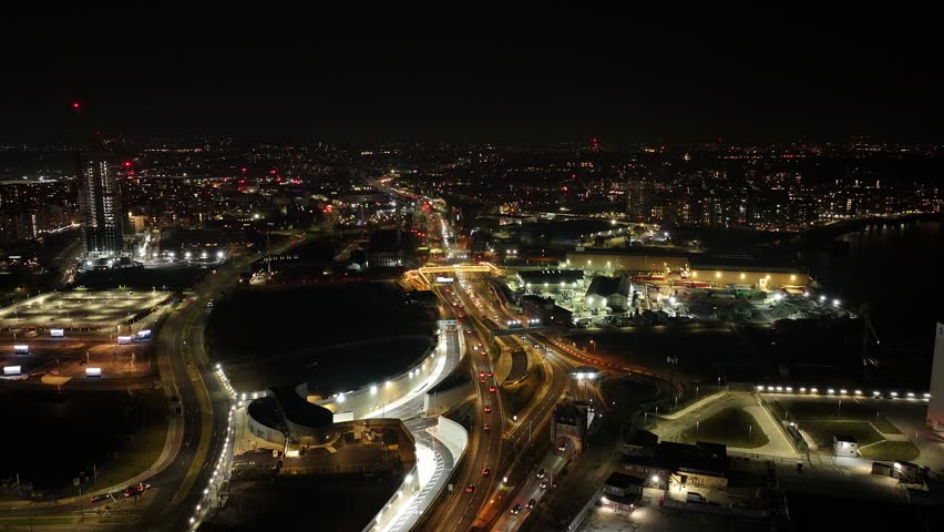Highway, cityscape and stadiums at O2 area in London at night, aerial