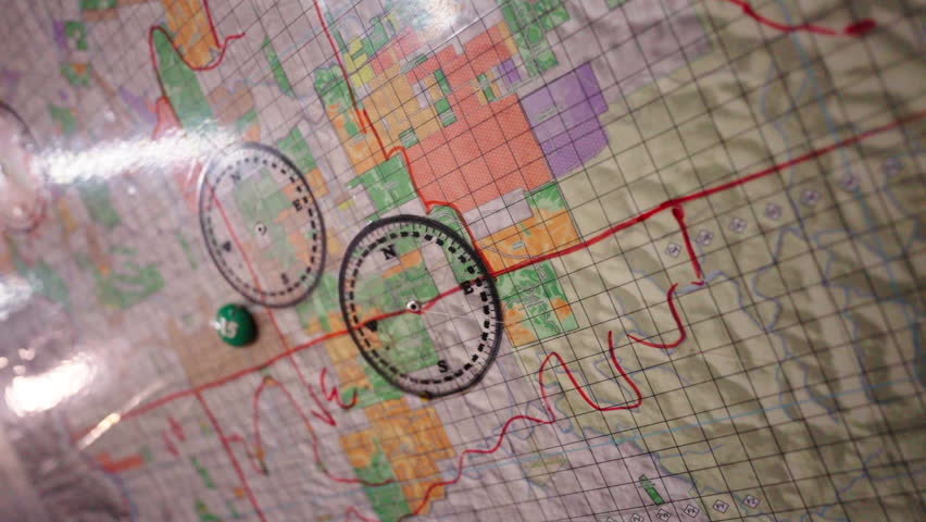 Close-up of a topographical map with compass and marker placed on it for navigation.