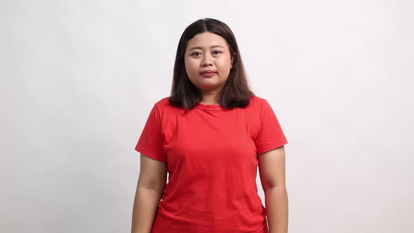 Happy Asian woman standing while pointing sideways on empty space and showing thumbs up. Isolated on white