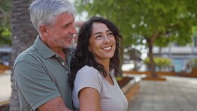 Middle aged couple embracing in city park with man and woman smiling under trees in outdoor urban setting showing love and connection - Powered by Shutterstock - Get 15% off with code: PIKWIZARD15