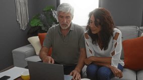 Middle-aged couple sitting together on a sofa using a laptop in a cozy living room setting, showcasing love, collaboration, and domestic bliss. - Powered by Shutterstock - Get 15% off with code: PIKWIZARD15