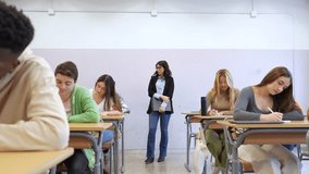 Students concentrating during supervised written exam, filling test papers while teacher monitors academic assessment in university classroom - Powered by Shutterstock - Get 15% off with code: PIKWIZARD15