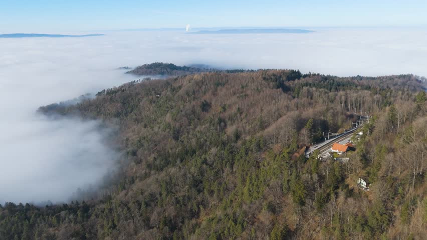 train station uetliberg zurich switzerland sits base remote forest covered mountain clouds fog create serene ambiance ideal for tourism panning shot forested foggy day aerial drone