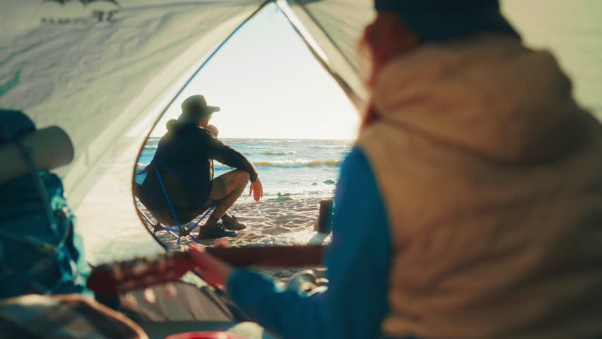 Summer happiness, people resting in camping on shore of sea or wide river. Travelers relaxing after long hike in nature, woman playing guitar, man listening to beautiful music and sounds of waves