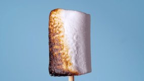 Marshmallow on Stick Burning, Covered with Black Crust, Sugar Bubbling and Smoking. Close-Up Roasting Candy on a Blue Background - Powered by Shutterstock - Get 15% off with code: PIKWIZARD15