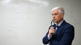 Mature man stands at a white board with written formulas.  - Powered by Shutterstock - Get 15% off with code: PIKWIZARD15