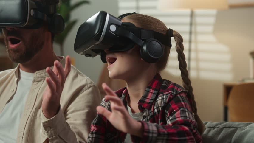 Excited Caucasian family father with emotional scared amazed daughter dad man male with kid girl child at home at couch enjoying online gaming play in VR helmet glasses virtual reality modern tech - Powered by Shutterstock - Get 15% off with code: PIKWIZARD15