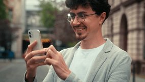 Positive smiling happy business male holding mobile phone scrolling social media reading sms good news message smile Hispanic guy Caucasian at street with smartphone businessman man outdoors at city - Powered by Shutterstock - Get 15% off with code: PIKWIZARD15