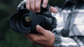 Professional photographer capturing image with professional grade digital camera, wearing lens hood, standing outdoors with soft focused landscape background - Powered by Shutterstock - Get 15% off with code: PIKWIZARD15