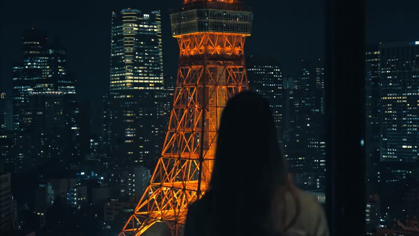 A serene moment of a girl gazing at the illuminated Tokyo Tower surrounded by the dazzling city skyline at night.