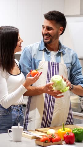 Young couple having fun preparing a healthy meal with fresh vegetables in their modern kitchen