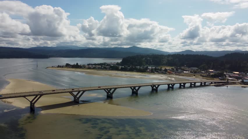 Alsea Bay Bridge spanning the Alsea River in Waldport, Oregon, along HWY 101. Cars Driving Across Bridge Crossing on Summer Day Pan to Bayshore. South of Newport, North of Florence and Yachats