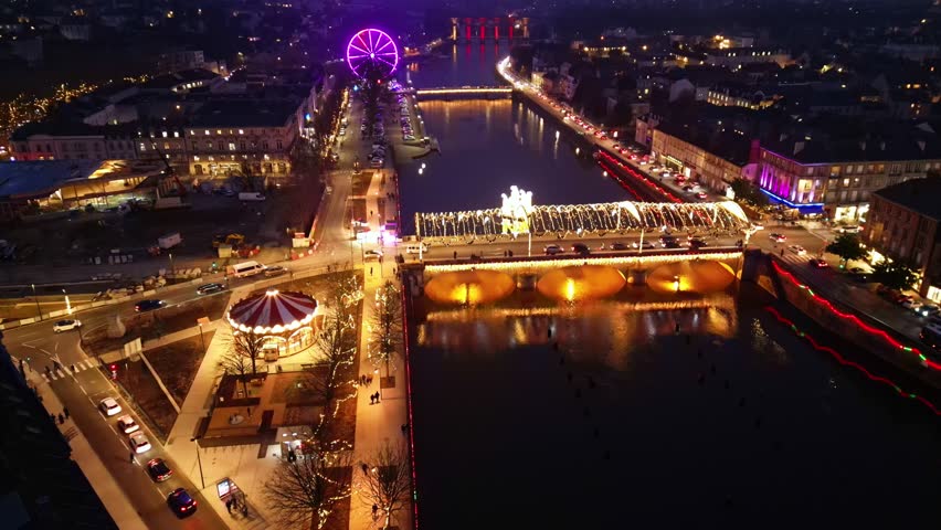Christmas lighted Aristide Briand bridge with carousel and big wheel on approaching drone movement, Laval, France.