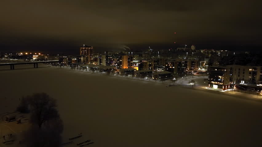 Aerial view rotating over the Pielisjoki river, winter night in Joensuu, Finland