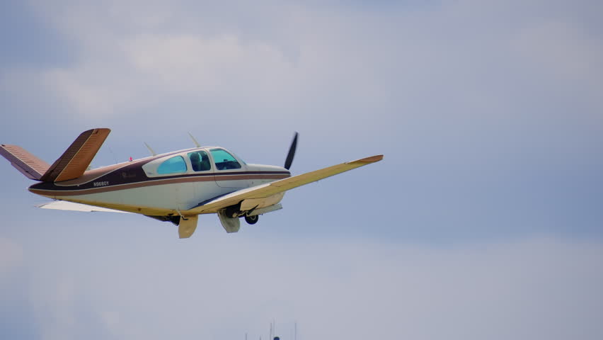 Propeller plane is flying at the small airport. Bright cloudy sky. 