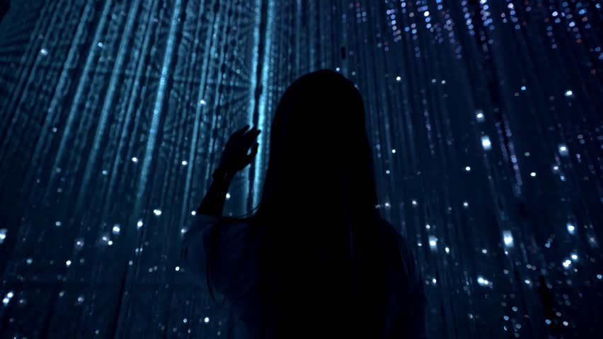A cinematic shot of a girl interacting with the illuminated blue lights art installation at TeamLab Planets in Tokyo.