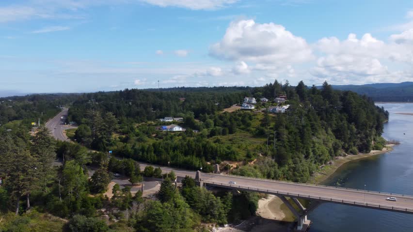 Alsea Bay Bridge spanning the Alsea River in Waldport, Oregon, along HWY 101. Cars Driving Across Bridge Crossing on Summer Day Pan to Bayshore. South of Newport, North of Florence and Yachats