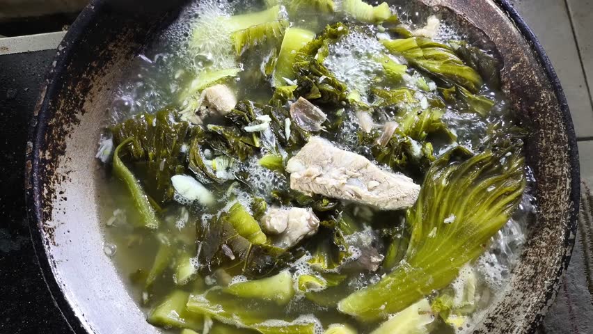 Cooking pickled lettuce soup in pan, in door Chiangmai Thailand.