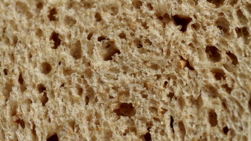 Detail of wheat bread and butter spread on it with a knife. Recorded with macro