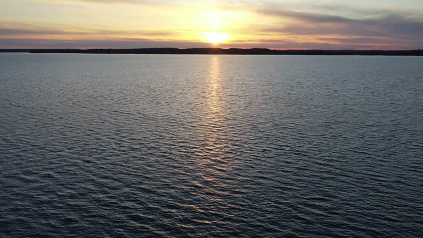 A serene sunset view over Lake Mendota in Madison, Wisconsin, showcasing rippling waters and a tranquil horizon.