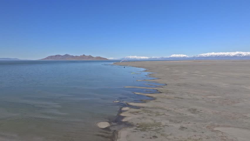 Aerial view of a paraglider soaring over the vast expanse of the Great Salt Lake in Utah, showcasing the unique landscape and the thrill of aerial sports