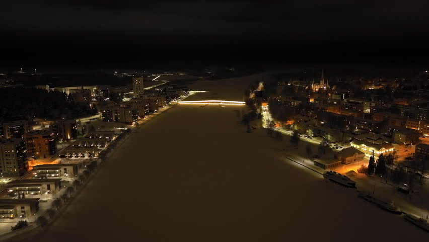 Drone flying toward the Ylisoutajan silta bridge, winter night in Joensuu, Finland