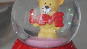 A teddy bear holding the word "LOVE" in a Valentine's Day-themed snow globe - Powered by Shutterstock - Get 15% off with code: PIKWIZARD15