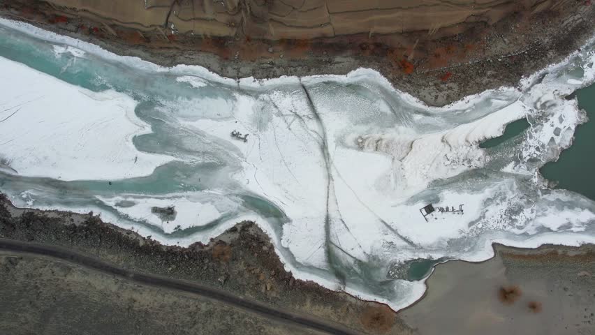 Birds eye view of frozen Indus river snaking through snowy landscape of Skardu Valley, showcasing nature