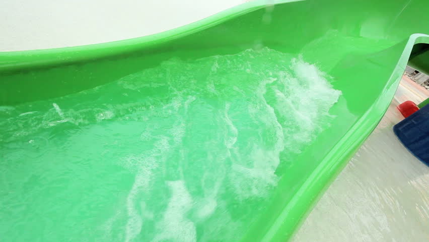 Young Caucasian girl laughing as she slides down plastic chute at water park