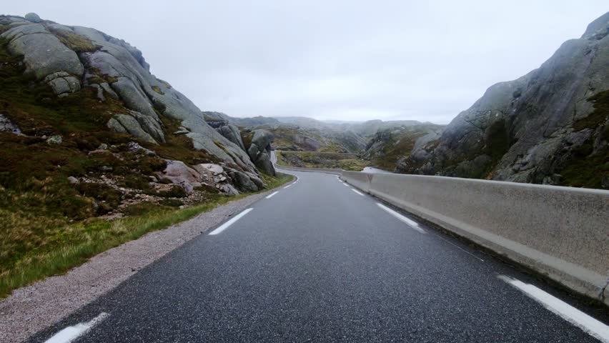 Driving along a wet, winding mountain road in Norway under an overcast sky, 4K