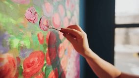 Professional artist delicately applying pink paint using palette knife, transforming large canvas with vibrant red rose details inside bright, creative studio workspace - Powered by Shutterstock - Get 15% off with code: PIKWIZARD15