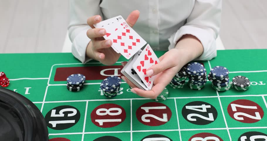 Female croupier shuffles playing card over roulette table. Woman prepares deal with casino chips on green betting field slow motion. Gambling game