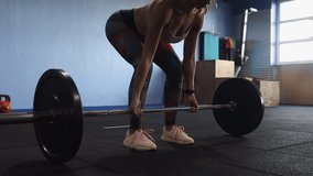 Low camera orbits woman in gym performing barbell deadlift exercise - Powered by Shutterstock - Get 15% off with code: PIKWIZARD15