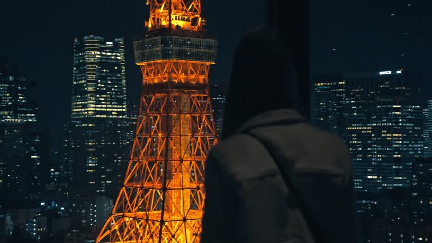 A serene moment of a girl gazing at the illuminated Tokyo Tower surrounded by the dazzling city skyline at night.