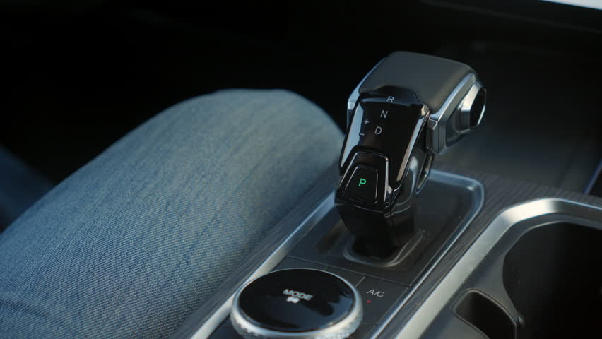 Close up view of man changing gears on automatic transmission in modern car.