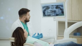 Professional dentist showing and explaining teeth x ray to patient on digital monitor in dental clinic, discussing diagnosis and treatment plan - Powered by Shutterstock - Get 15% off with code: PIKWIZARD15