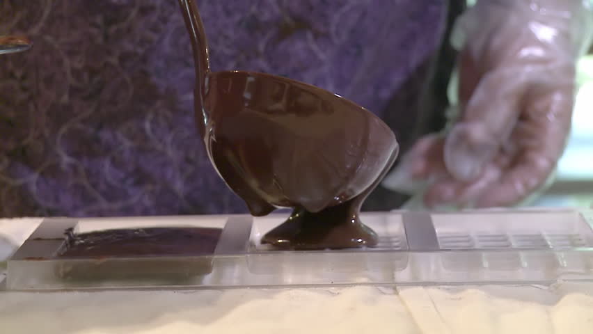 Slow motion view of chocolate being poured into a mould to make chocolate bars.