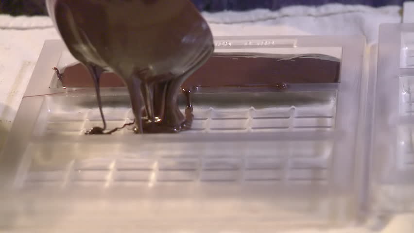 Slow motion view of liquid chocolate being poured into a mould to make chocolate
