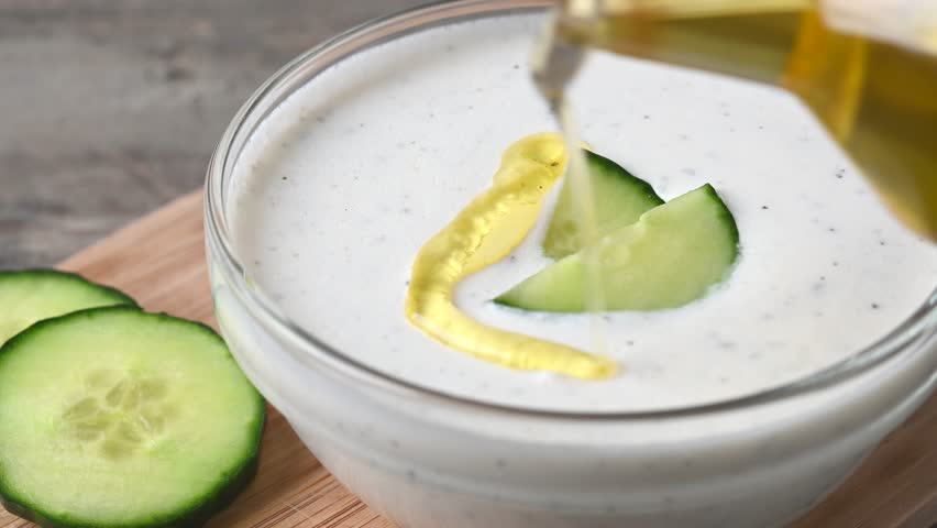  Pouring olive oil on greek Tzatziki sauce on wooden table