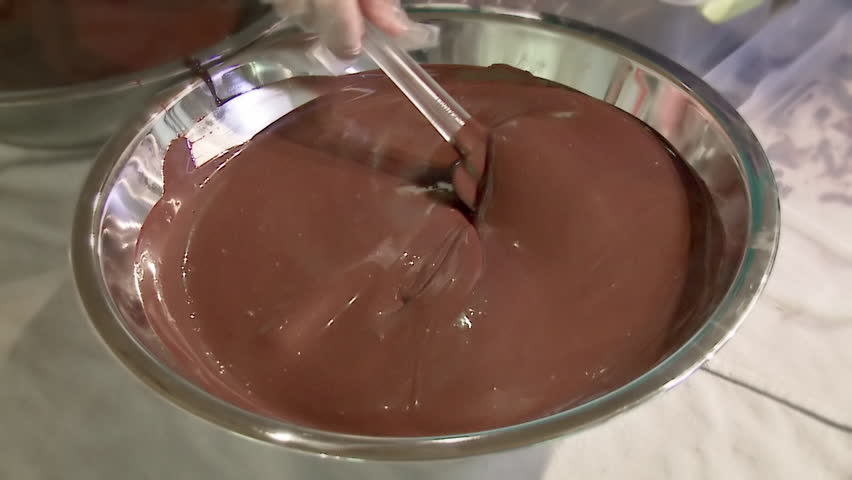 Stirring liquid chocolate with pre-made bars of chocolate, tempering it, which
