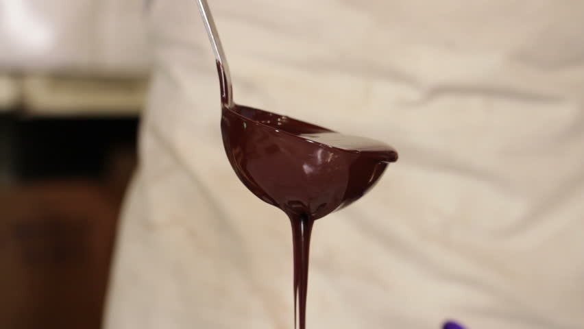 Pouring chocolate with a ladle. Close up on ladle.
