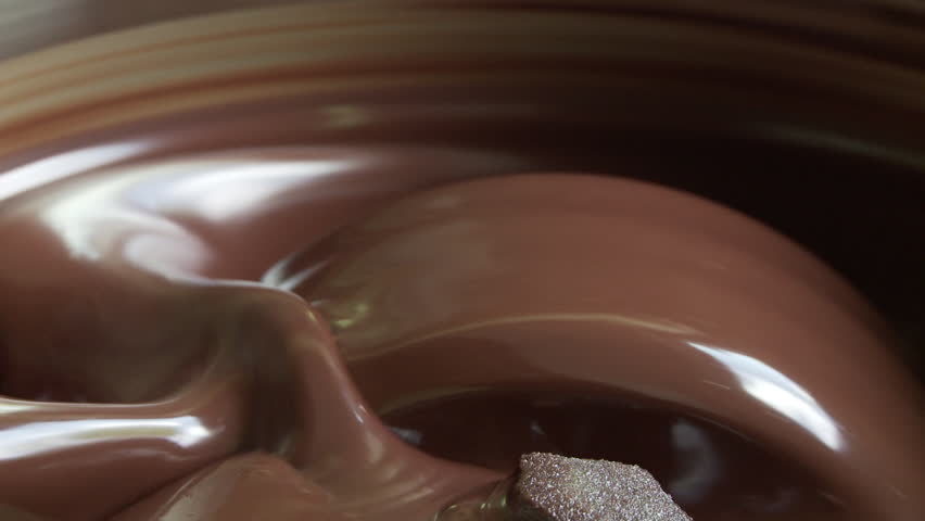 Side view showing chocolate turning over and over in a steel bowl, blending and