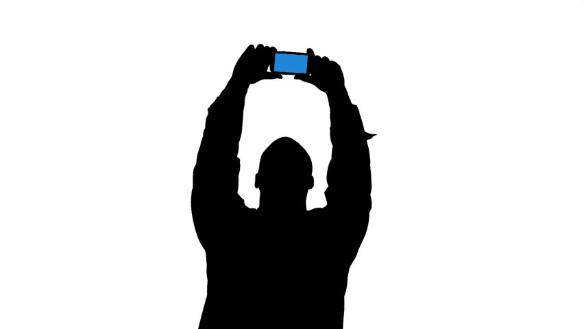 Silhoutted man taking pictures or video with a cellphone. Black and white