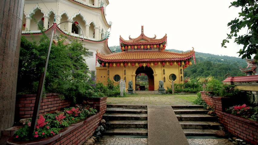 Kek lok si temple entrance decorated with red and yellow lanterns and statues, located on penang island, malaysia. Translation: Best wishes for a long, healthy life and a rich future