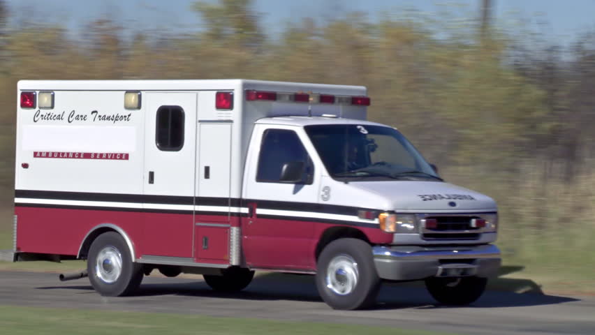 Ambulance arriving at destination on a country road with lights flashing in