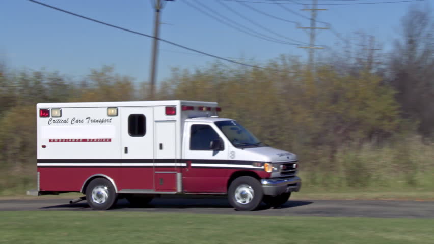 Ambulance arriving at destination on a country road with lights flashing in