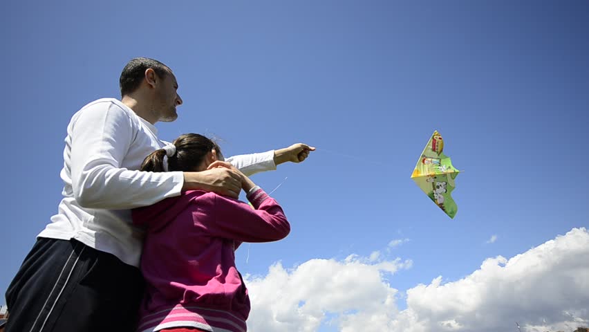 Young family flies kite together, wide angle
