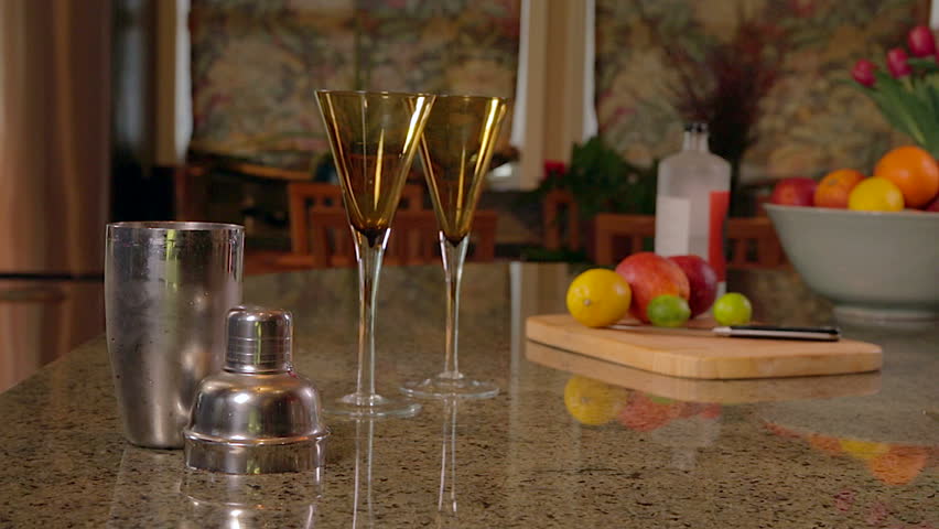 Woman shaking cocktail mixture and pouring into glasses
