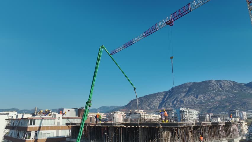 Aerial Video: Cranes Operating on a Large Construction Site With Workers Pouring Concrete for New Structures