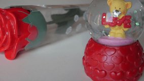 A Valentine’s themed snow globe with a teddy bear holding a “LOVE” sign, and a red rose - Powered by Shutterstock - Get 15% off with code: PIKWIZARD15